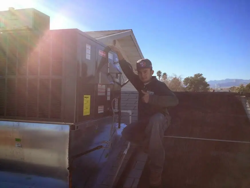 HVAC technician performing Air Duct Cleaning on a rooftop unit in Grass Valley